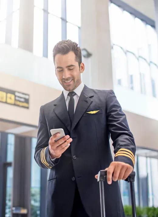 Piloto em aeroporto mexendo em celular